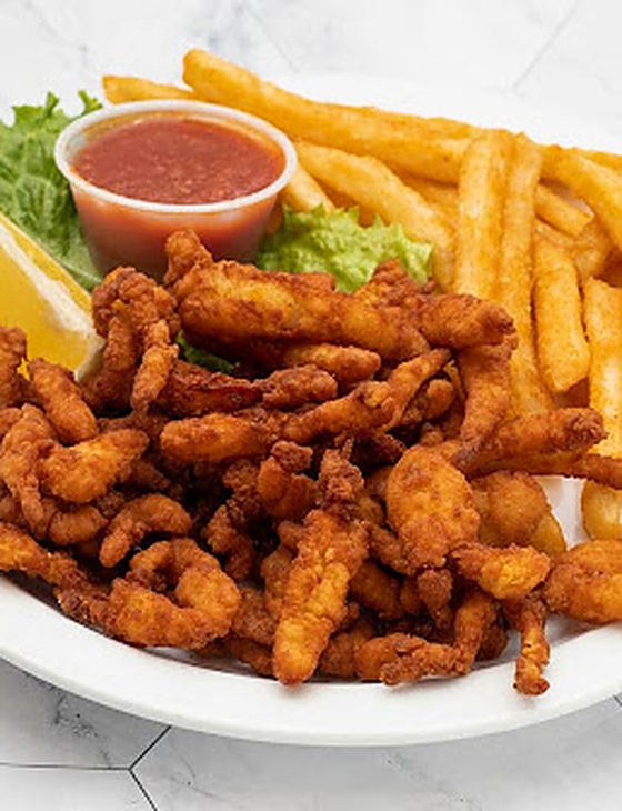 A plate piled with golden fried clam strips, fries, lettuce, lemon and cocktail sauce