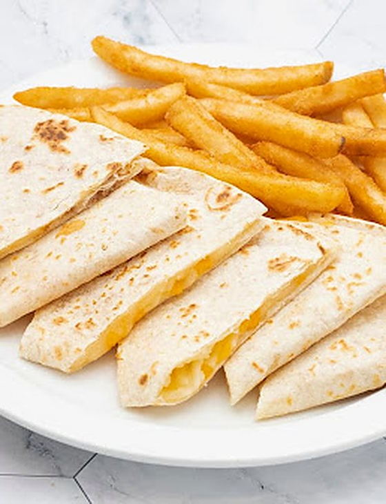 A cheese quesadilla cut into wedges, served with a side of fries